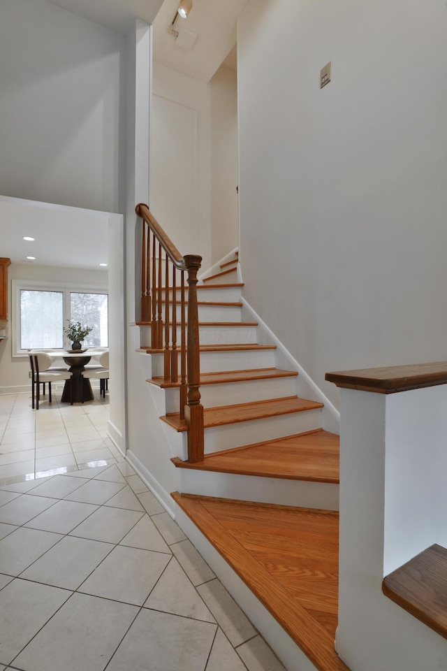 staircase featuring a towering ceiling, baseboards, and tile patterned floors