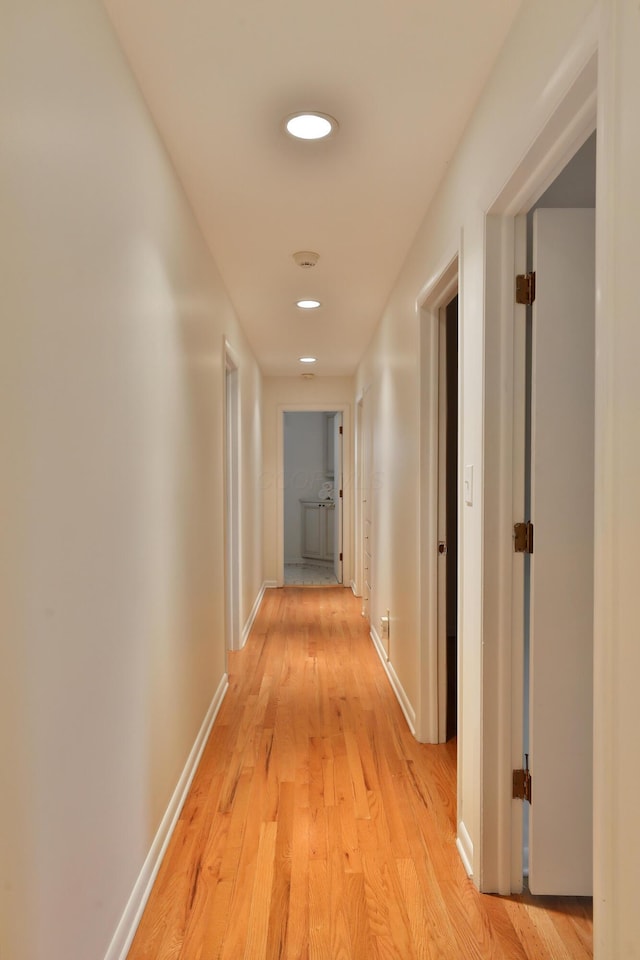 hallway with baseboards, recessed lighting, and light wood-style floors