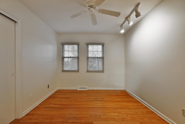 spare room with ceiling fan, light wood-type flooring, visible vents, and baseboards