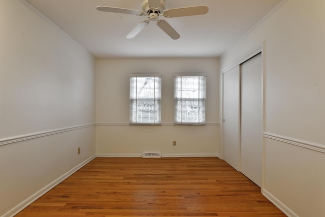 unfurnished bedroom featuring baseboards, visible vents, a ceiling fan, wood finished floors, and a closet