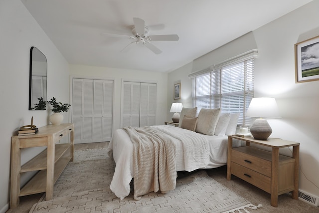 bedroom featuring a ceiling fan, visible vents, and two closets