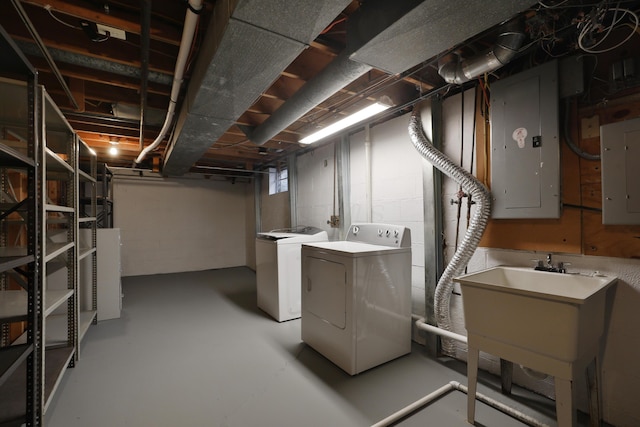 basement with electric panel, washer and clothes dryer, and a sink