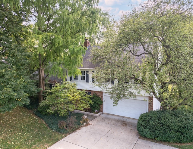 obstructed view of property featuring driveway, a shingled roof, a chimney, an attached garage, and brick siding