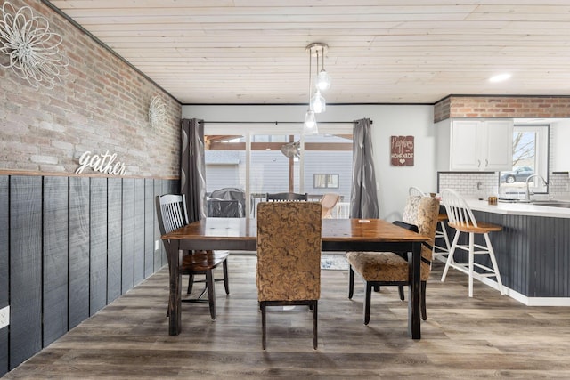 dining area featuring wood ceiling, brick wall, and wood finished floors