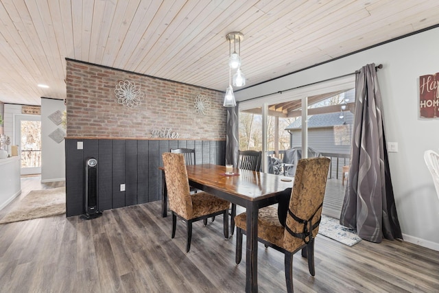 dining room with wood ceiling, brick wall, baseboards, and wood finished floors