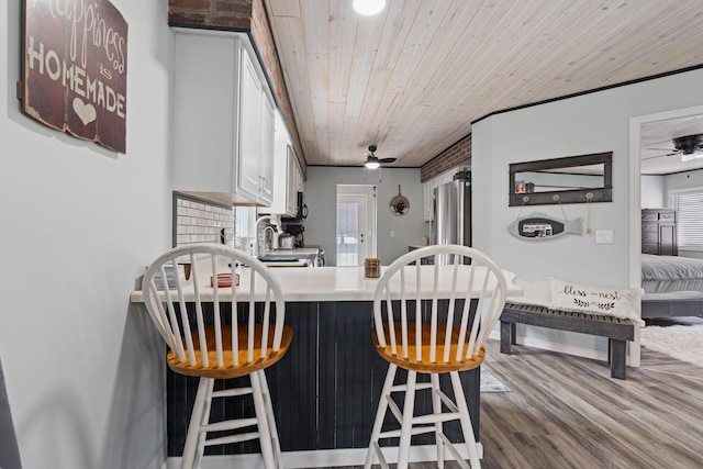 kitchen featuring white cabinets, wood ceiling, wood finished floors, a peninsula, and light countertops