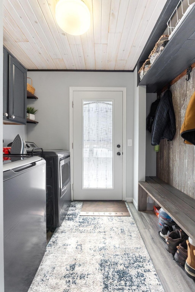 washroom with cabinet space, wood ceiling, washer and clothes dryer, and wood finished floors