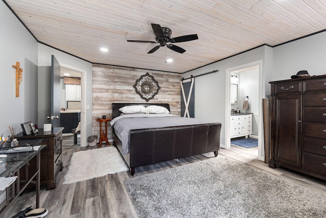 bedroom with wood finished floors, wooden ceiling, crown molding, and a barn door