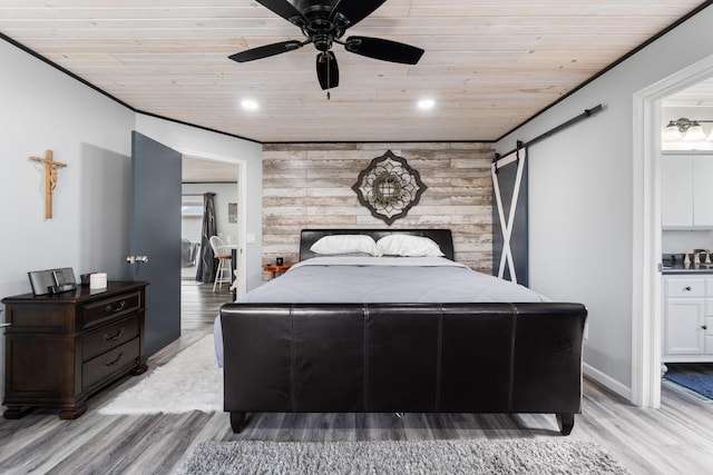 bedroom featuring a barn door, wooden ceiling, an accent wall, light wood-type flooring, and recessed lighting