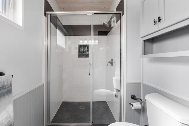 bathroom featuring a wainscoted wall, a shower stall, and toilet