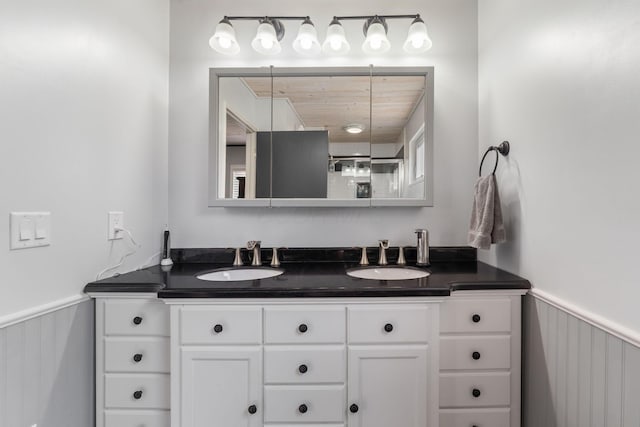 bathroom with a wainscoted wall, a sink, and double vanity