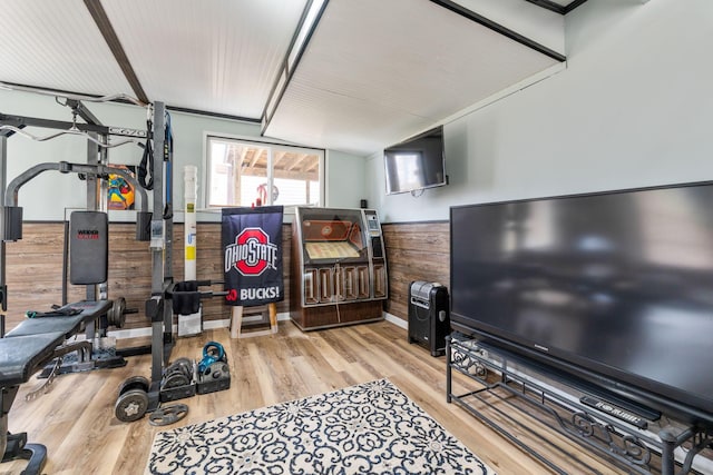 exercise room with wooden walls, wood finished floors, and wainscoting