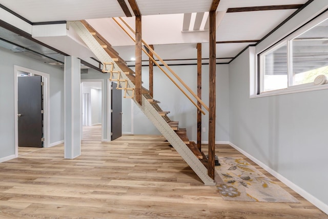 below grade area featuring light wood-type flooring, baseboards, and stairs