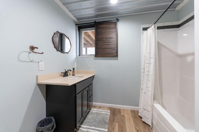 full bath with shower / tub combo, baseboards, wood finished floors, and vanity