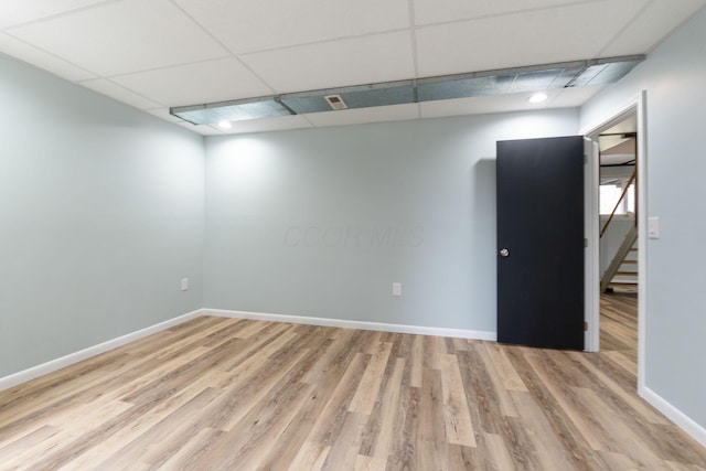 unfurnished room with stairs, baseboards, a drop ceiling, and wood finished floors