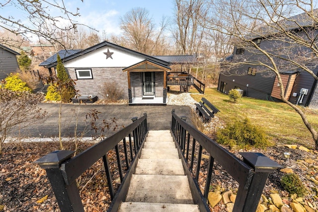 view of front of property featuring stone siding, stairs, and a front yard