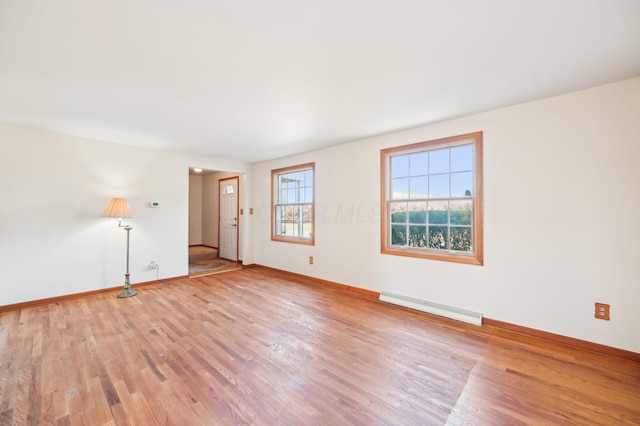 empty room featuring light wood-style floors, baseboards, and baseboard heating