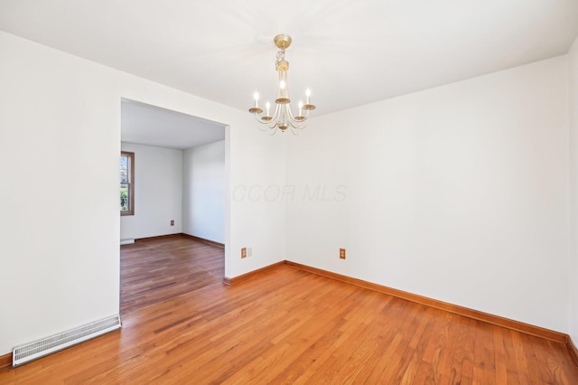 spare room with visible vents, baseboards, an inviting chandelier, and light wood-style flooring