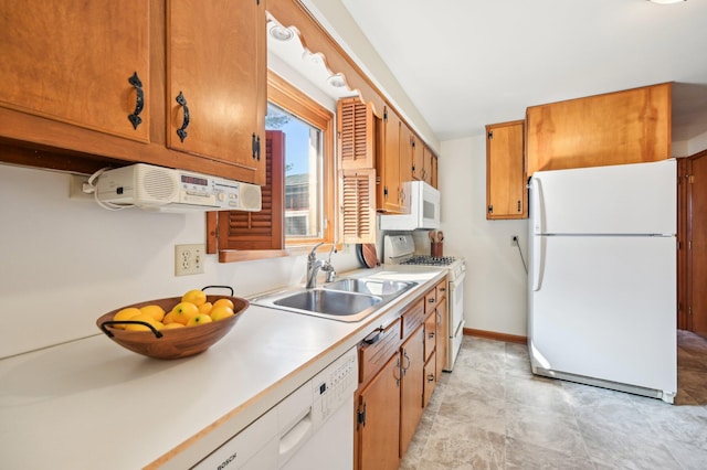 kitchen with a sink, white appliances, brown cabinets, and light countertops