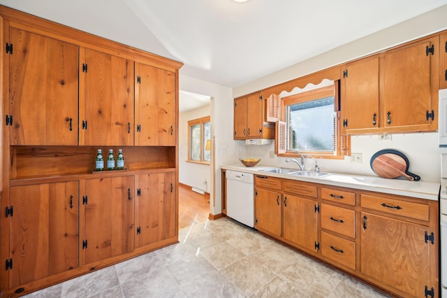 kitchen with a sink, white appliances, brown cabinetry, and light countertops