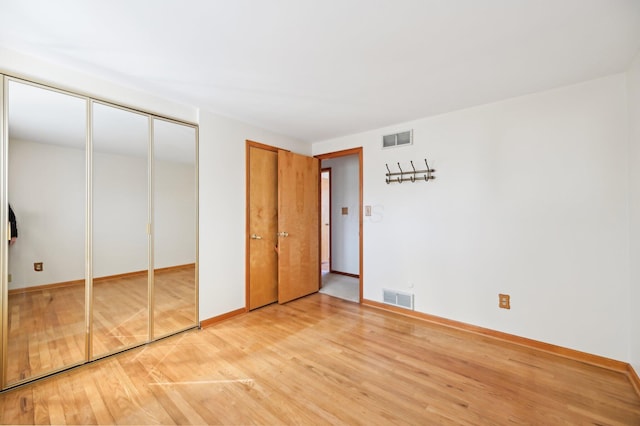 unfurnished bedroom with visible vents, multiple closets, baseboards, and light wood-style flooring