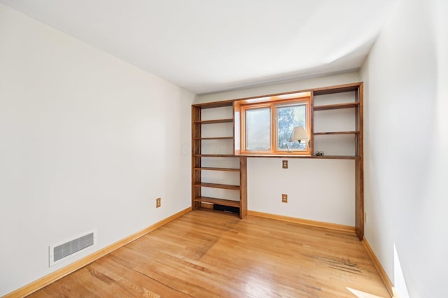 unfurnished room with visible vents, light wood-style flooring, and baseboards