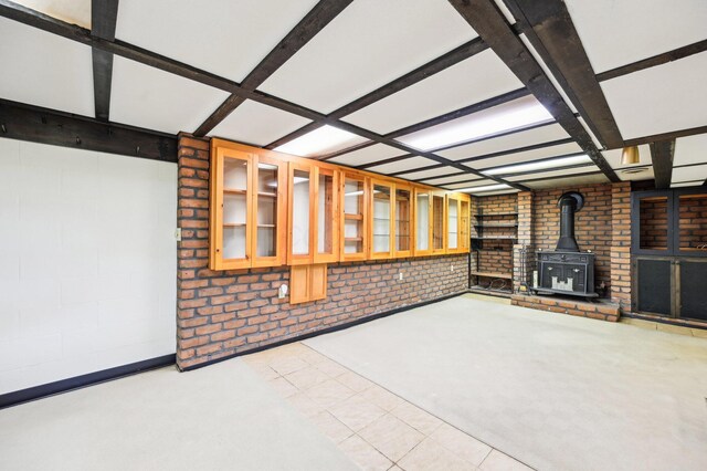 unfurnished living room with a wood stove and brick wall