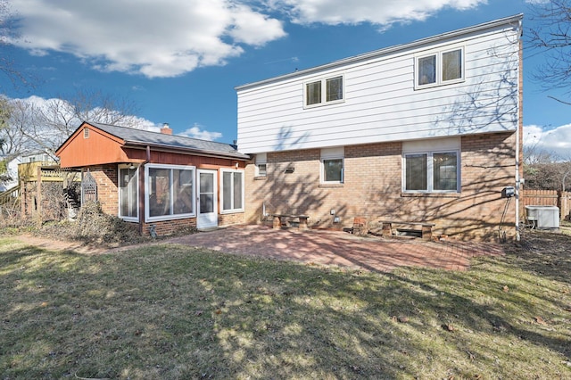 rear view of house featuring fence, a lawn, and brick siding