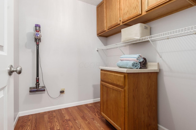 interior space featuring cabinet space, baseboards, and wood finished floors