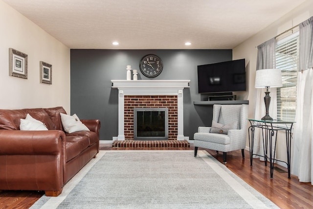 living room featuring a fireplace, recessed lighting, a textured ceiling, wood finished floors, and baseboards