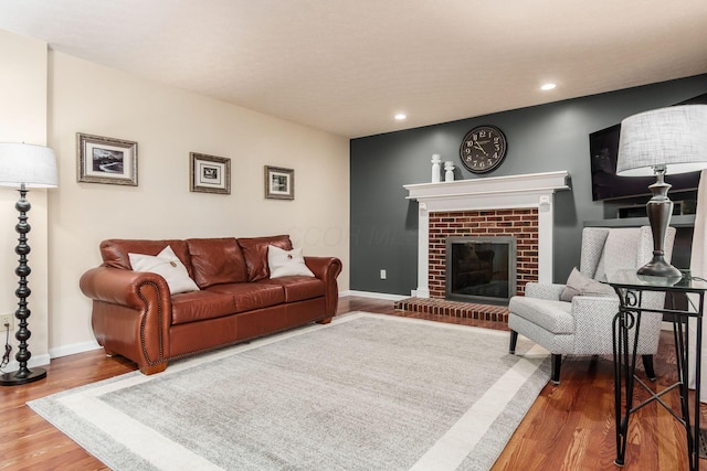 living room featuring recessed lighting, a brick fireplace, wood finished floors, and baseboards