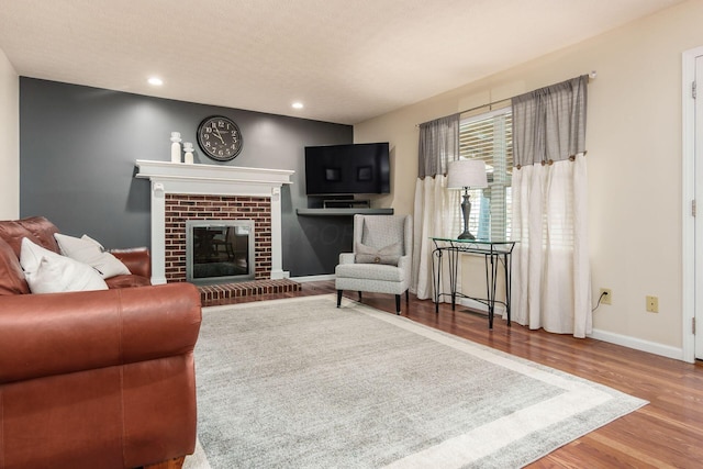 living room featuring recessed lighting, a fireplace, wood finished floors, and baseboards