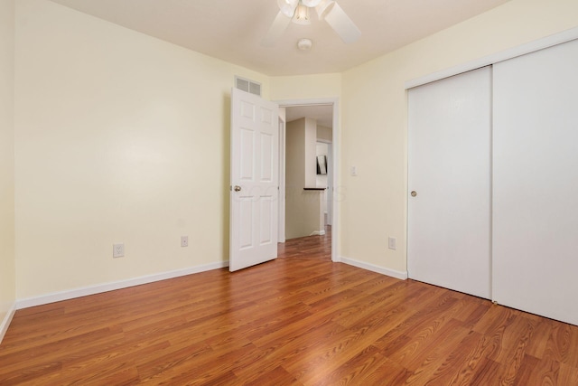 unfurnished bedroom featuring a closet, visible vents, ceiling fan, and light wood-style flooring