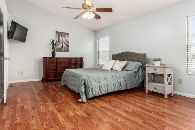 bedroom featuring a ceiling fan, vaulted ceiling, baseboards, and wood finished floors