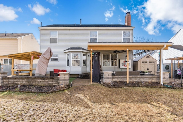 rear view of property with a ceiling fan, an outbuilding, a patio, and a chimney