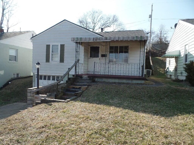 view of front of property featuring a garage, covered porch, a front yard, and central air condition unit