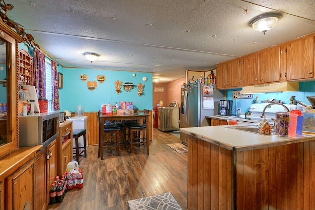 kitchen featuring sink, hardwood / wood-style flooring, washer / clothes dryer, and a textured ceiling