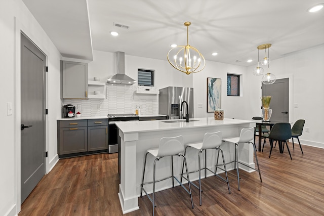 kitchen featuring appliances with stainless steel finishes, gray cabinets, wall chimney range hood, and visible vents