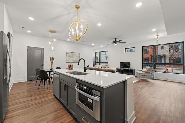 kitchen featuring recessed lighting, wood finished floors, a sink, light countertops, and appliances with stainless steel finishes