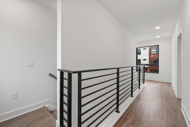 hallway with recessed lighting, baseboards, an upstairs landing, and wood finished floors