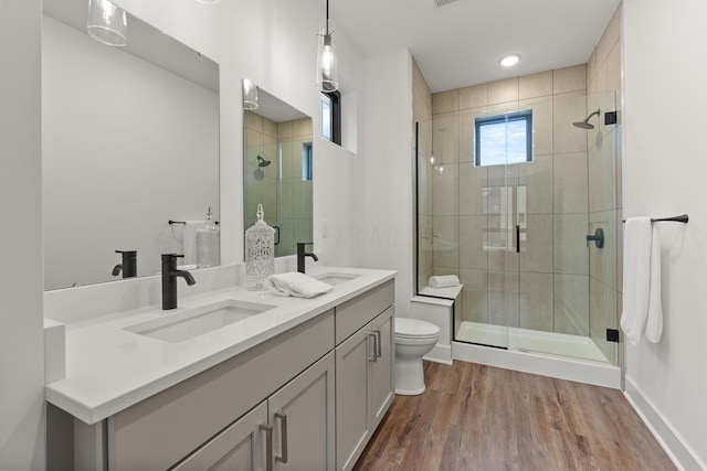 bathroom with wood finished floors, a stall shower, a sink, and toilet