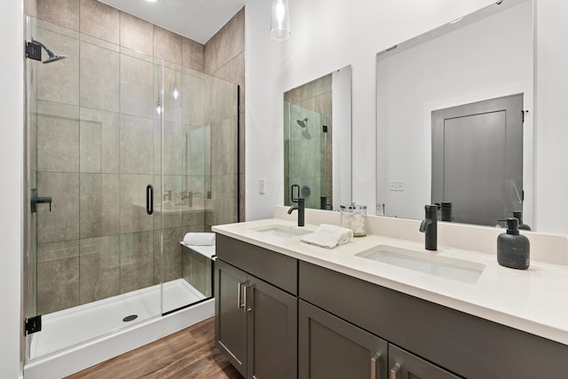 full bathroom with a stall shower, a sink, and wood finished floors