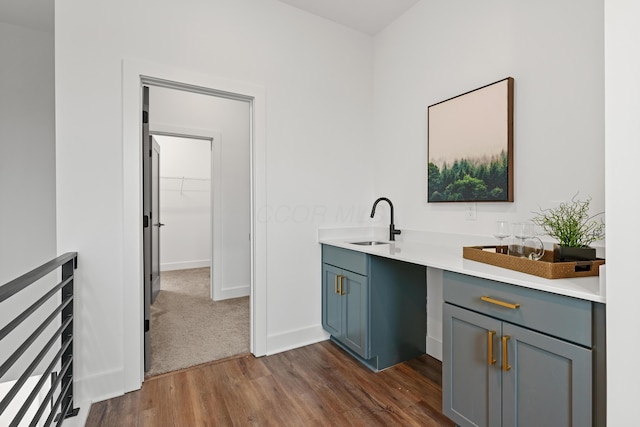 bar with dark wood-style flooring, a sink, and baseboards