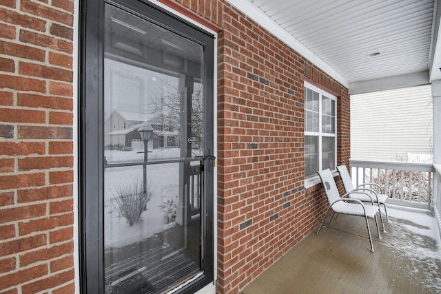 snow covered property entrance with a porch