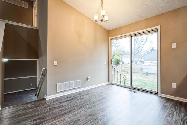 unfurnished room featuring an inviting chandelier, lofted ceiling, and dark hardwood / wood-style floors