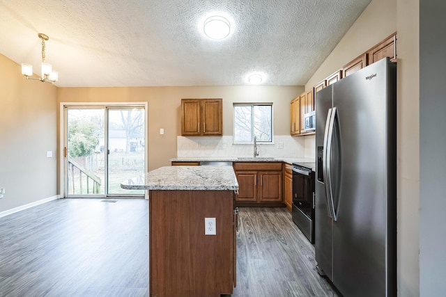 kitchen featuring sink, hanging light fixtures, appliances with stainless steel finishes, a kitchen island, and backsplash