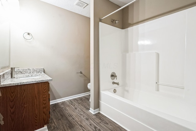 full bathroom featuring hardwood / wood-style floors, washtub / shower combination, vanity, toilet, and a textured ceiling