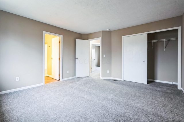 unfurnished bedroom featuring ensuite bathroom, carpet flooring, a closet, and a textured ceiling