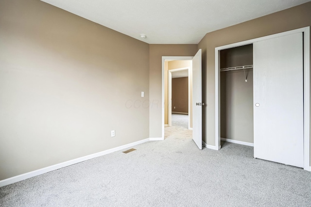 unfurnished bedroom with light colored carpet and a closet