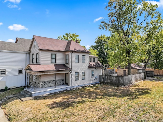 rear view of house with a patio and a lawn